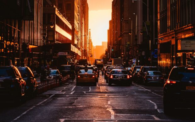 Street view of a New York sunset with busy traffic and tall buildings lining the road