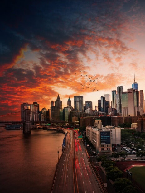 New York sunset casting vibrant colors over the city skyline and busy highway