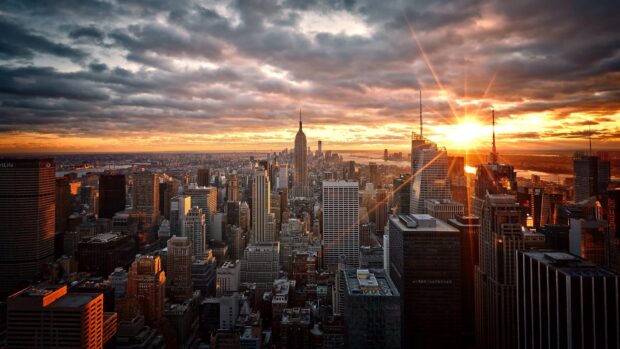 New York sunset view with city skyline and glowing sun rays through clouds