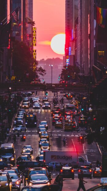 The New York sunset creates a calming scene over busy streets and high rise buildings