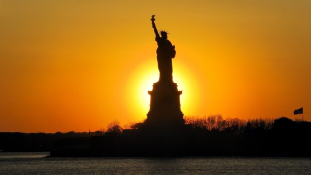 Statue of Liberty silhouette during New York sunset with vibrant orange sky