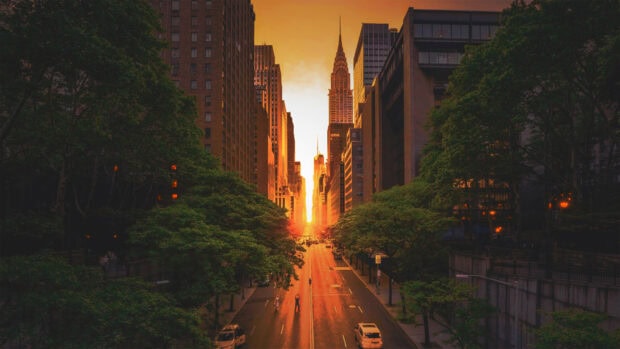 The New York sunset view shines brightly between tall buildings on a city street