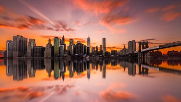 New York sunset view with city skyline and reflections on calm water at dusk