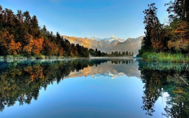 Clear lake reflecting mountains and autumn trees in New Zealand
