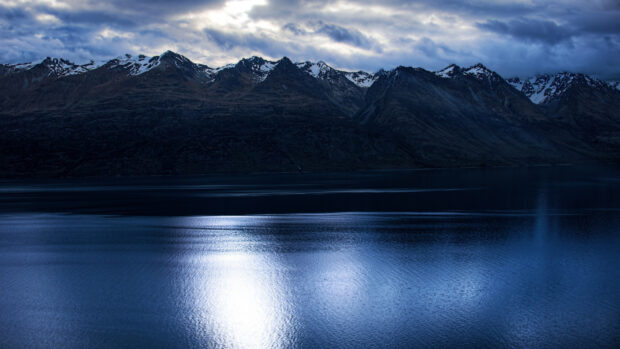 Snow capped mountains reflect over the calm lake in New Zealand landscape
