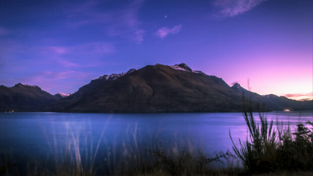Purple twilight over New Zealand mountain landscape with lake and clear sky stars