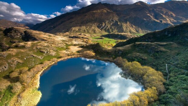 Serene New Zealand landscape with mountains and a clear lake reflecting the sky
