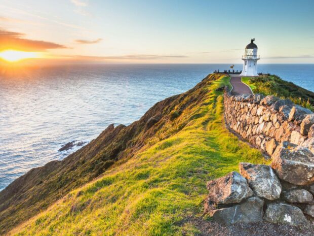 A scenic coastal landscape with a lighthouse on a cliff in New Zealand
