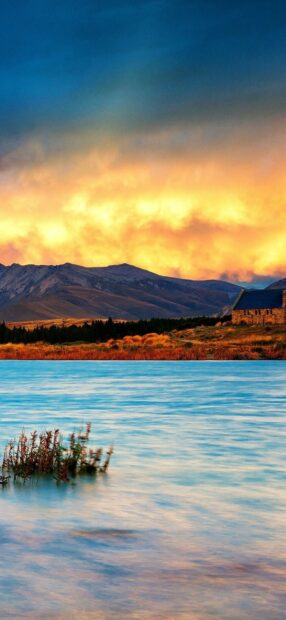 A tranquil New Zealand landscape with lake mountains and a sunset sky