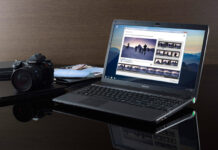 A Sony laptop showing a photo editing software with a digital camera nearby on a reflective surface