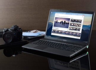 A Sony laptop showing a photo editing software with a digital camera nearby on a reflective surface