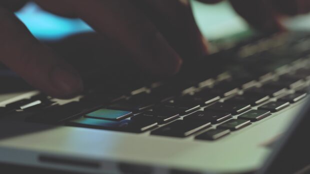Close up of hand typing on notebook keyboard in low light environment