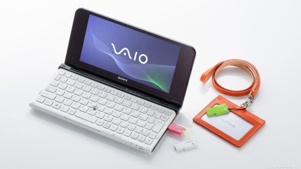 A white notebook with a digital screen showing the VAIO logo and colorful USB drives alongside an orange ID pass holder