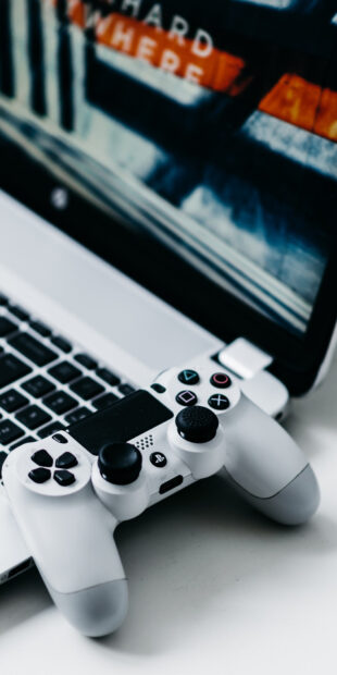 White game controller placed on a laptop keyboard with the screen in the background