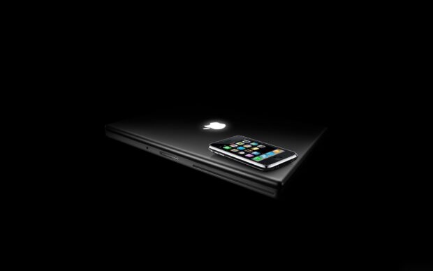 A sleek black notebook with a glowing logo and a smartphone placed on top in a dark environment