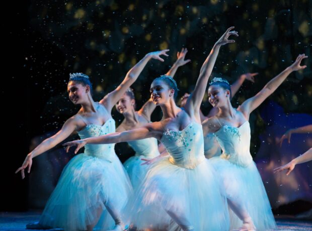 A group of ballet dancers performing a scene from Nutcracker on stage