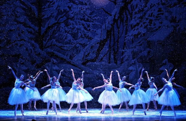 Ballet dancers performing a Nutcracker scene on stage in elegant white tutus