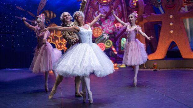 Ballet dancers performing in a Nutcracker ballet stage with colorful festive decorations