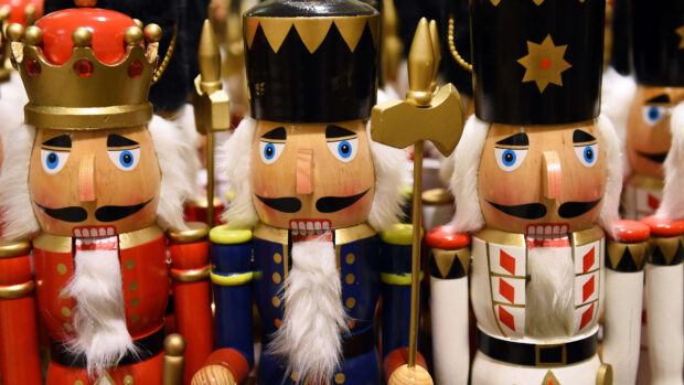 Wooden nutcracker figures with white beards and colorful uniforms standing side by side