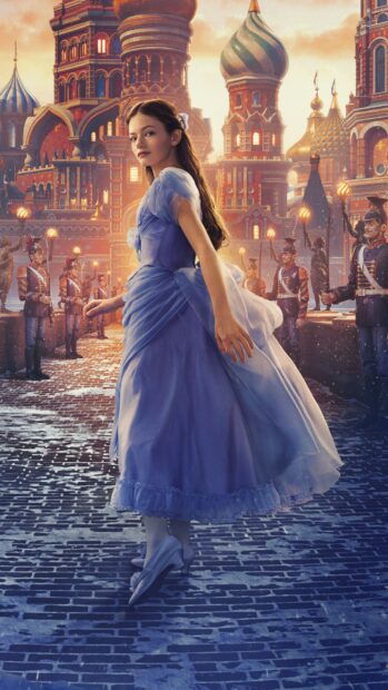 A young girl in a blue dress walking in front of toy soldiers and Russian architecture