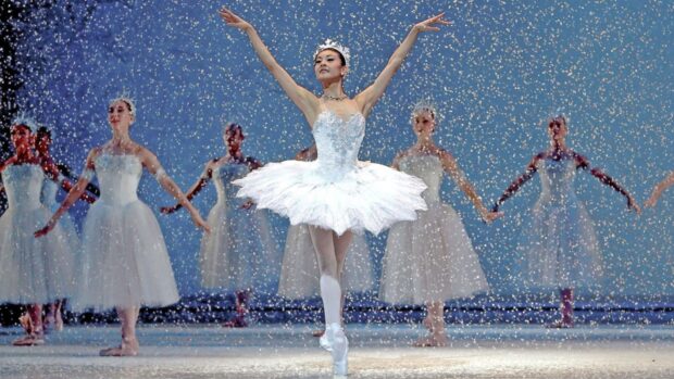 A ballerina dancing in a white tutu during a snow scene in a Nutcracker ballet performance