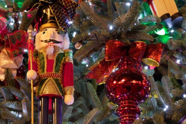 A traditional nutcracker figure decorated with gold and green details on a Christmas tree