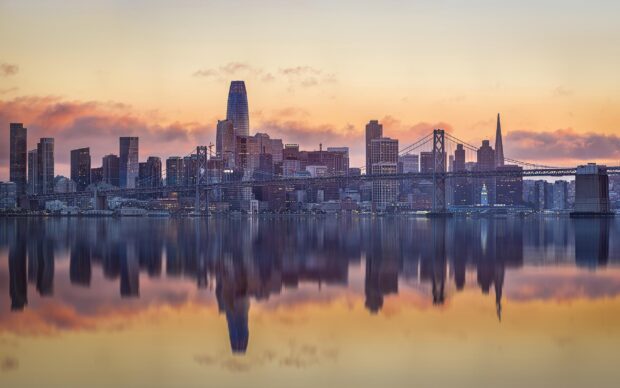 Stunning Oakland skyline at sunset with reflections on calm water and clear skies