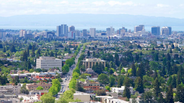 A clear view of Oakland skyline with cityscape and green trees under blue sky