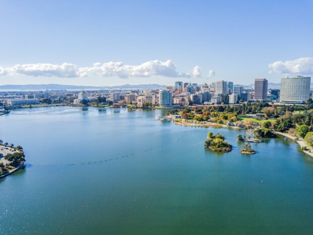 A panoramic view of Oakland skyline with clear blue sky and water in the foreground