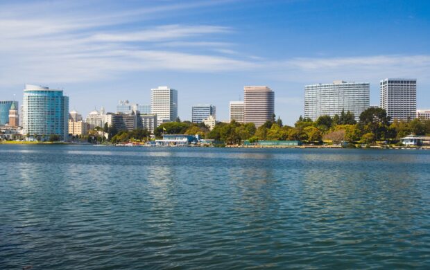 A panoramic view of Oakland skyline with clear blue sky and water reflecting the buildings