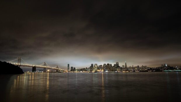 Night view of Oakland skyline with bridge and city lights reflecting on water