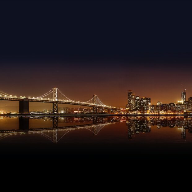 Beautiful Oakland skyline at night with illuminated buildings and bridge reflection