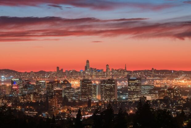 Stunning Oakland skyline with colorful sunset and city lights glowing in the evening sky