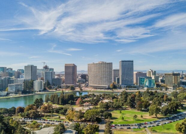 The Oakland city skyline with tall buildings and a large park in front on a clear day