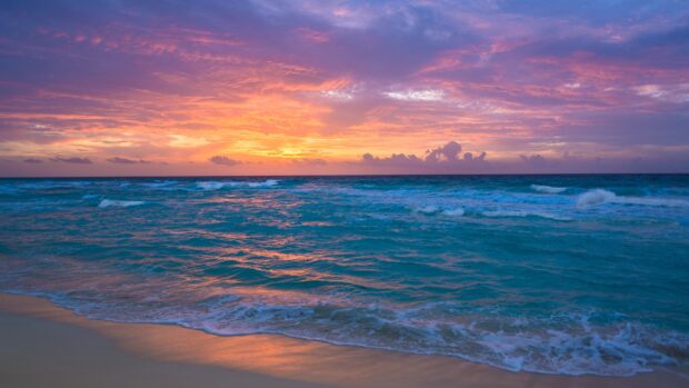 A beautiful ocean landscape with waves gently crashing on the shore during a colorful sunset