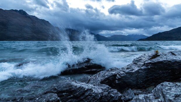 Ocean landscape with waves crashing against rocks under cloudy sky