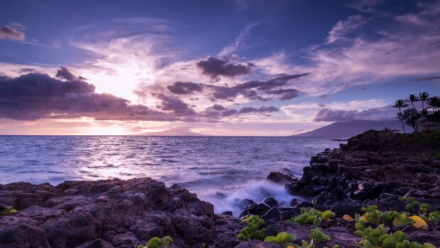 Rocky coast with ocean landscape under a cloudy sky at sunset