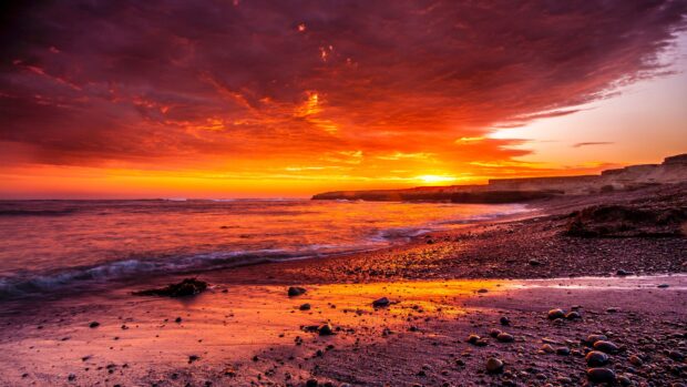 Rocky shore with ocean landscape under glowing sunset sky