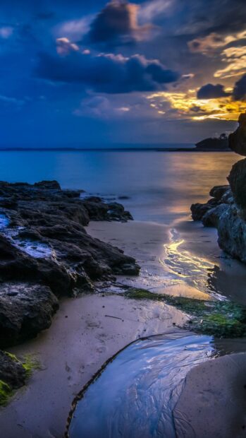 Peaceful ocean landscape with rocky shore and calm water at sunset