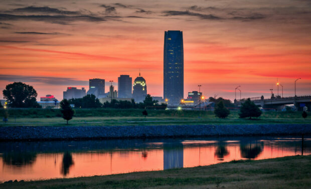 Oklahoma City skyline reflecting on calm water during a vibrant sunset
