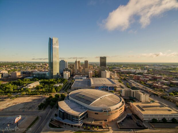 Oklahoma City skyline featuring tall buildings and the Chesapeake Arena under a clear blue sky