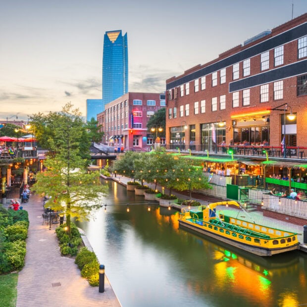 View of Oklahoma City skyline with river and colorful buildings at dusk