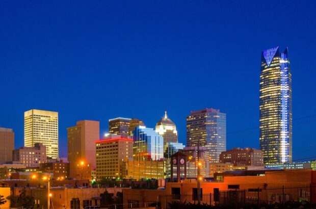 Oklahoma City skyline at dusk with illuminated buildings and clear blue sky