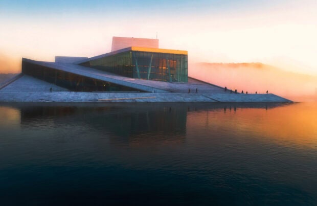 Modern architecture of Oslo Opera House with foggy river at sunrise in Oslo