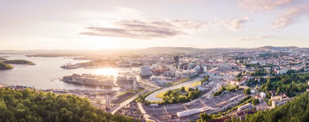 A panoramic view of Oslo cityscape with river and urban buildings under a bright sky