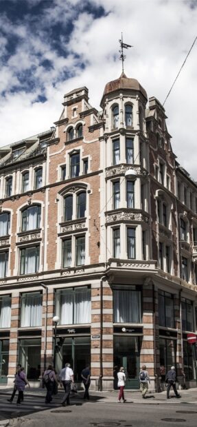 Historic ornate brick building with detailed windows and a weather vane in Oslo city center