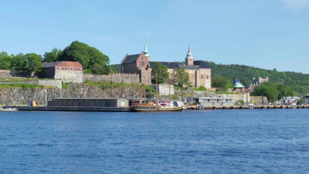 Historic Oslo castle by the waterfront with green trees and blue sky in Oslo