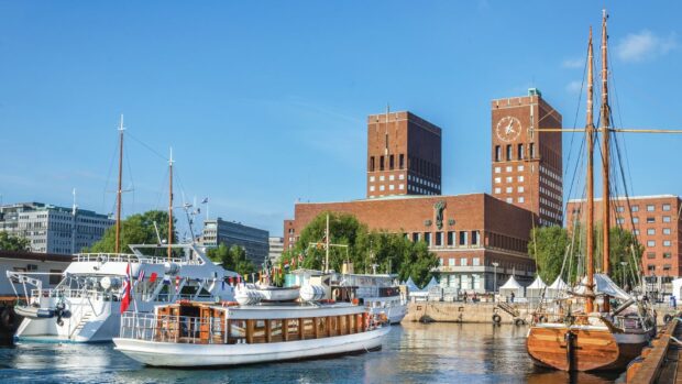 The Oslo city hall and boats docked at the harbor in clear sunny weather