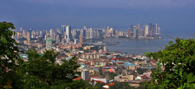 A panoramic view of Panama City skyline with urban buildings and green trees surrounding