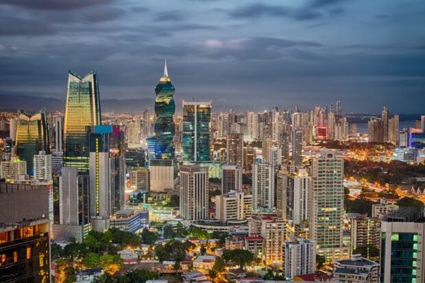 Nighttime cityscape of Panama City skyline with tall buildings and vibrant lights in the evening